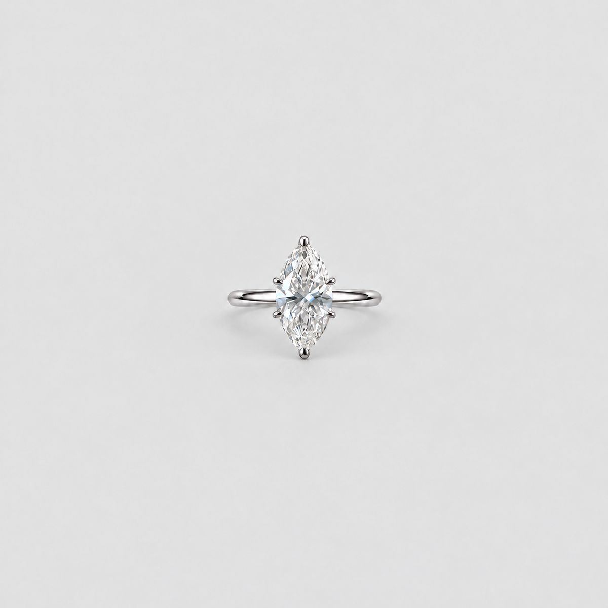 A single marquise-cut diamond engagement ring in a silver-toned setting, centered on a light gray background.