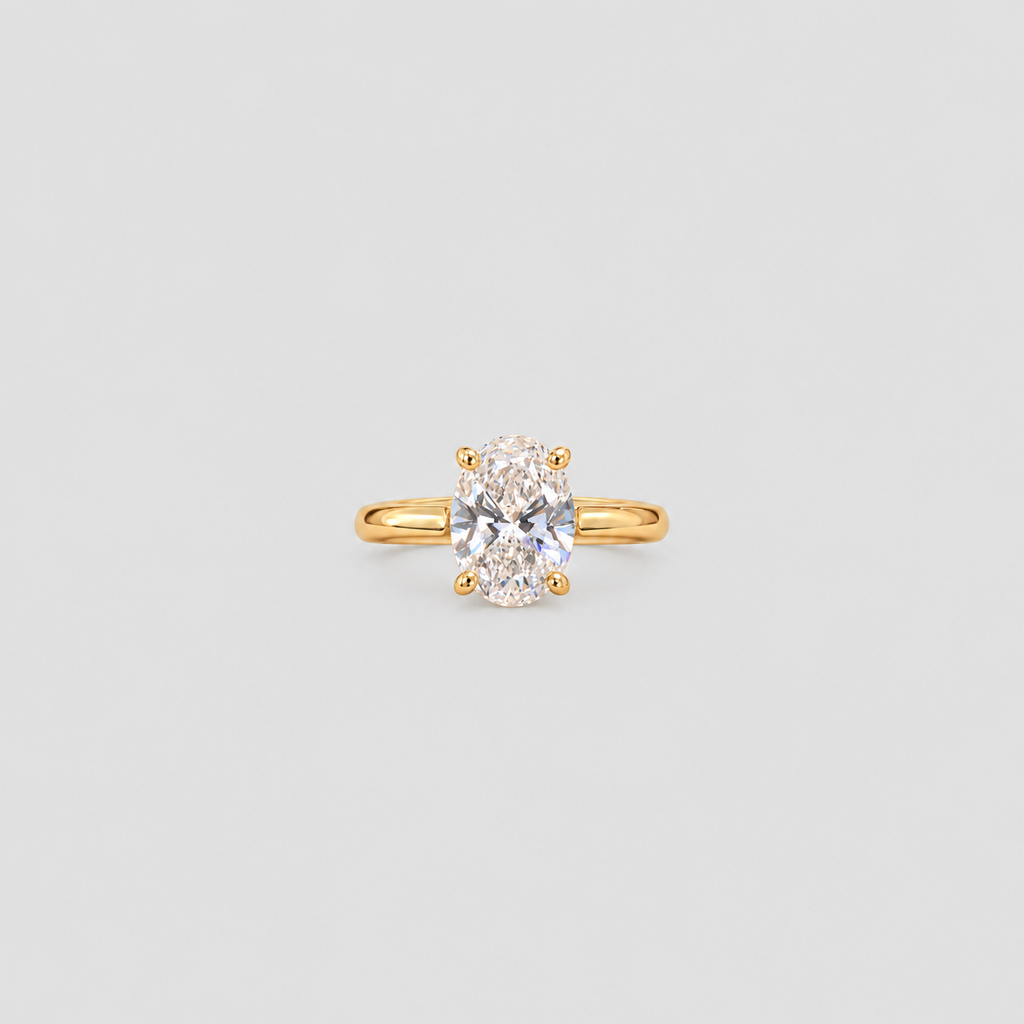 A yellow gold solitaire ring featuring an oval-cut clear gemstone in a four-prong setting, centered on a light gray background.