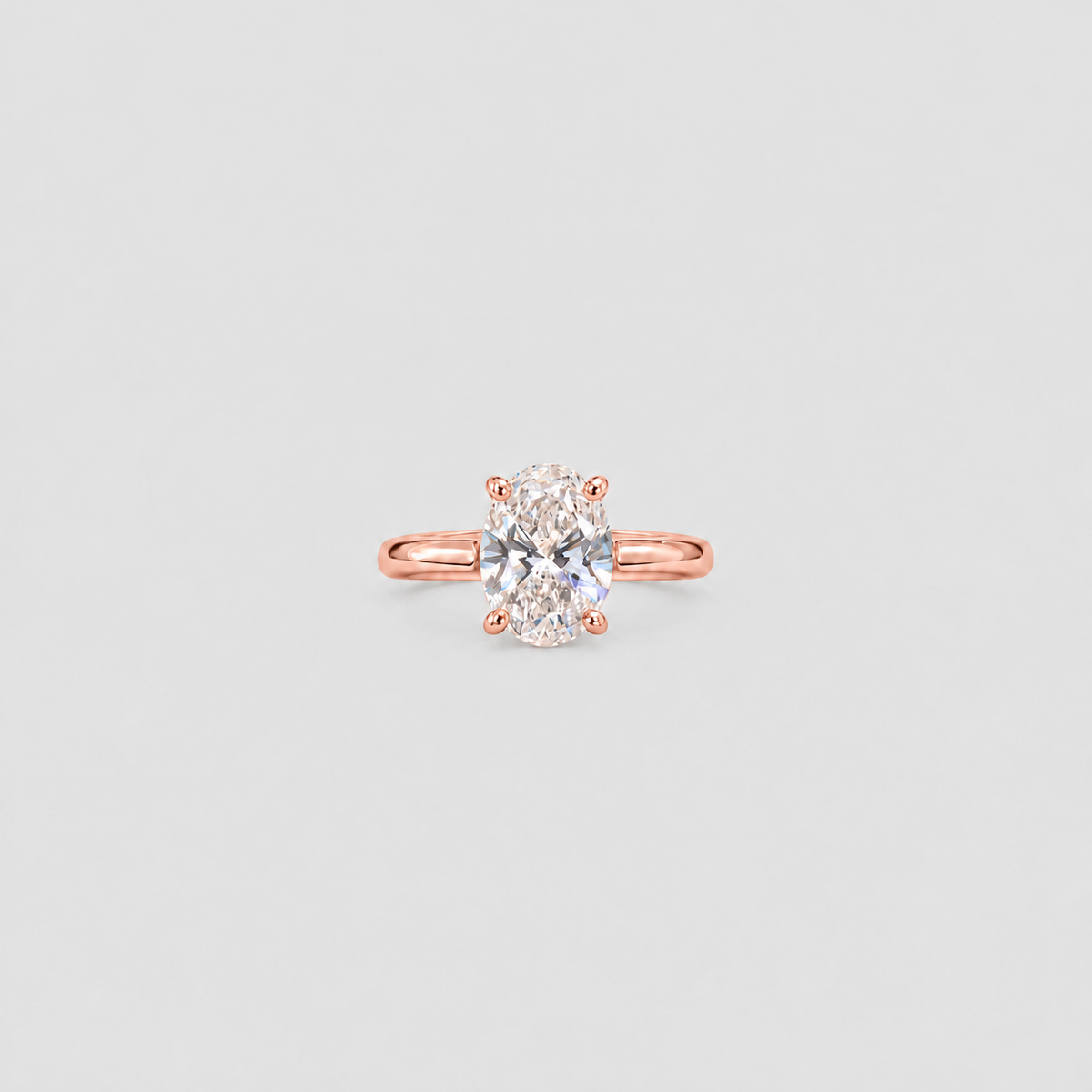 A single solitaire engagement ring featuring a round brilliant-cut diamond set in a rose gold four-prong setting, centered on a light gray background.