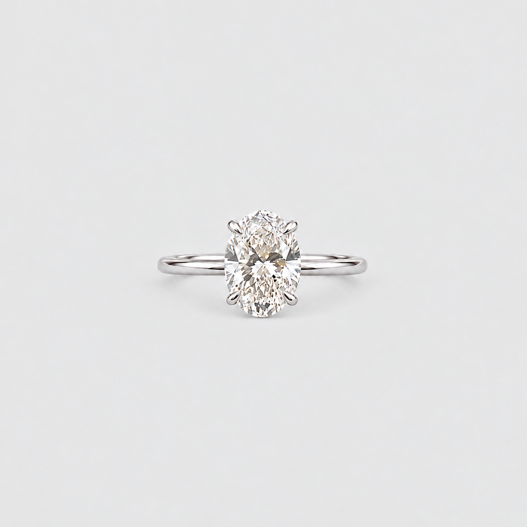 A classic solitaire engagement ring featuring an oval-cut diamond set in a polished silver-colored metal band, centered on a light gray background.