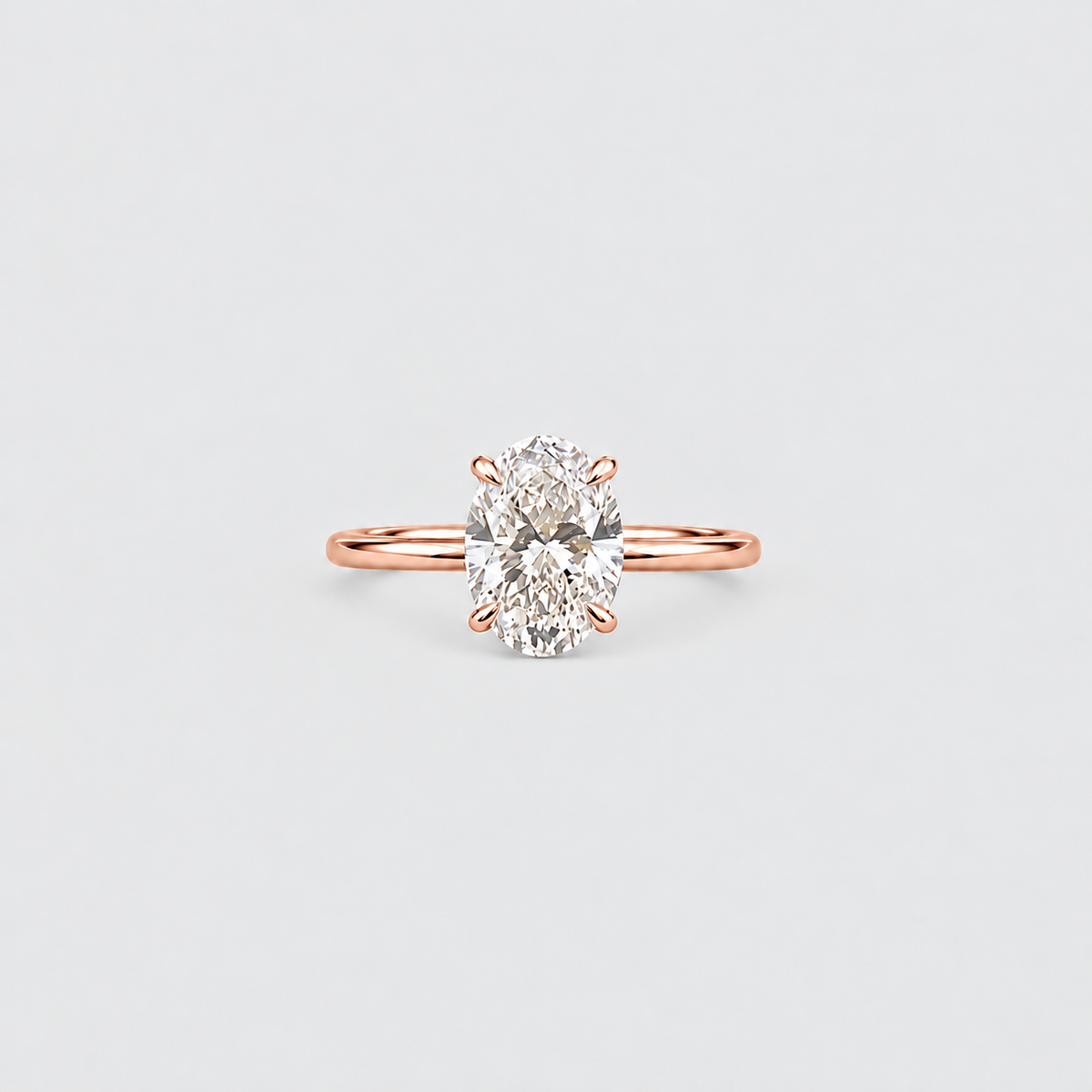 A rose gold engagement ring featuring a large oval-cut diamond set in a four-prong setting, centered on a light gray background.