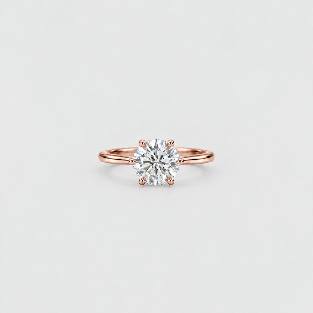 A classic solitaire engagement ring featuring a round brilliant-cut diamond set in a rose gold four-prong band, centered on a light gray background.