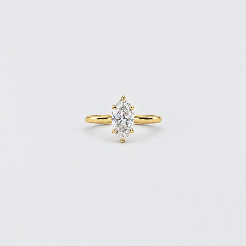 A yellow gold ring featuring a marquise-cut clear gemstone in a prong setting, centered on a clean, light gray background.