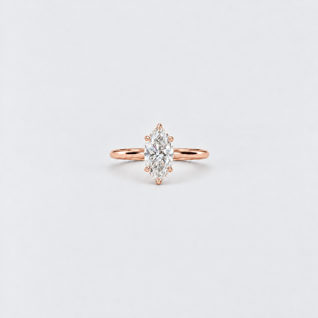 A rose gold ring featuring a marquise-cut diamond center stone in a prong setting, shown on a clean, light gray background.