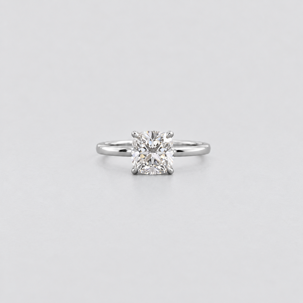 A classic solitaire engagement ring featuring a brilliant round-cut diamond set in a polished silver-colored band, centered against a light gray background.