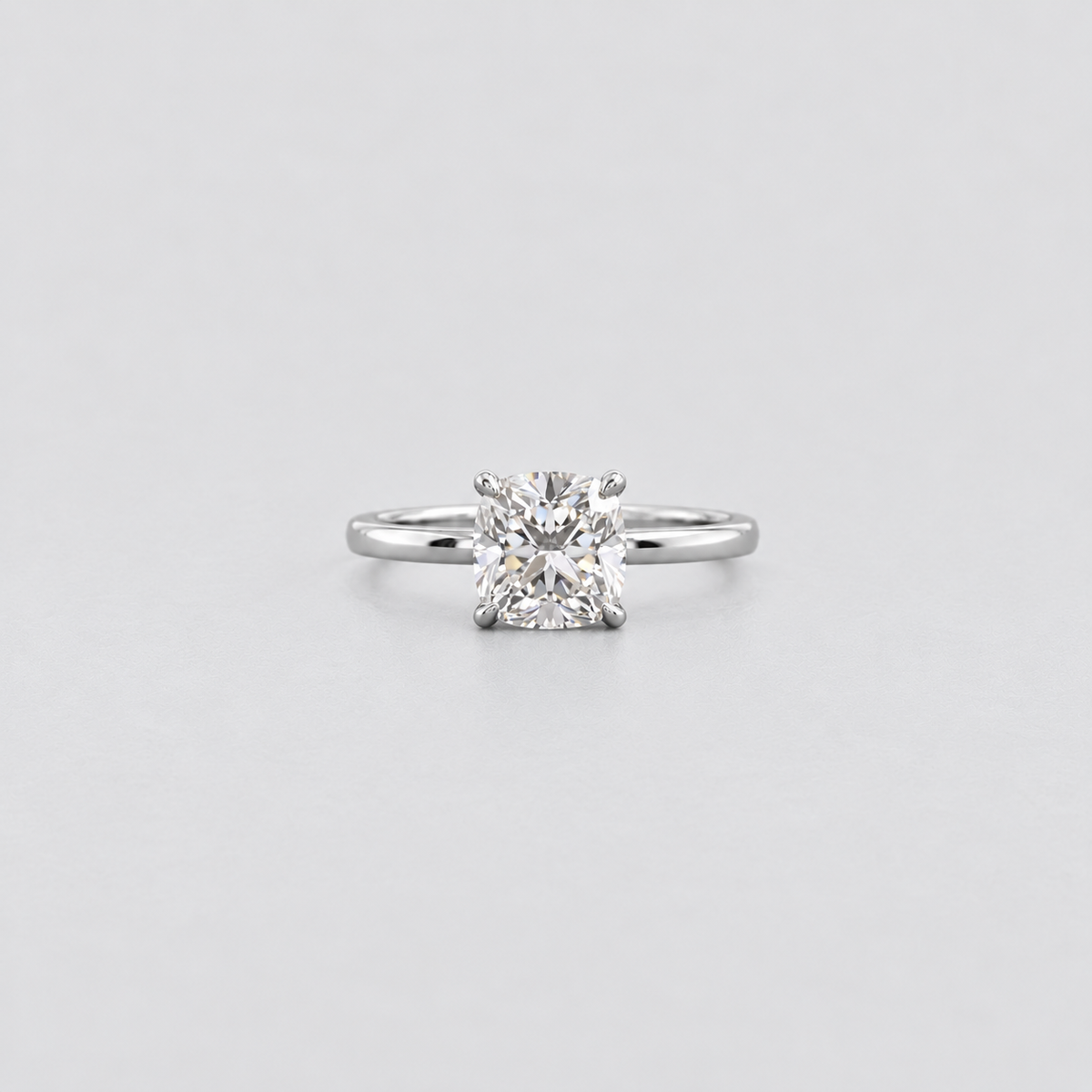 A classic solitaire engagement ring featuring a brilliant round-cut diamond set in a polished silver-colored band, centered against a light gray background.