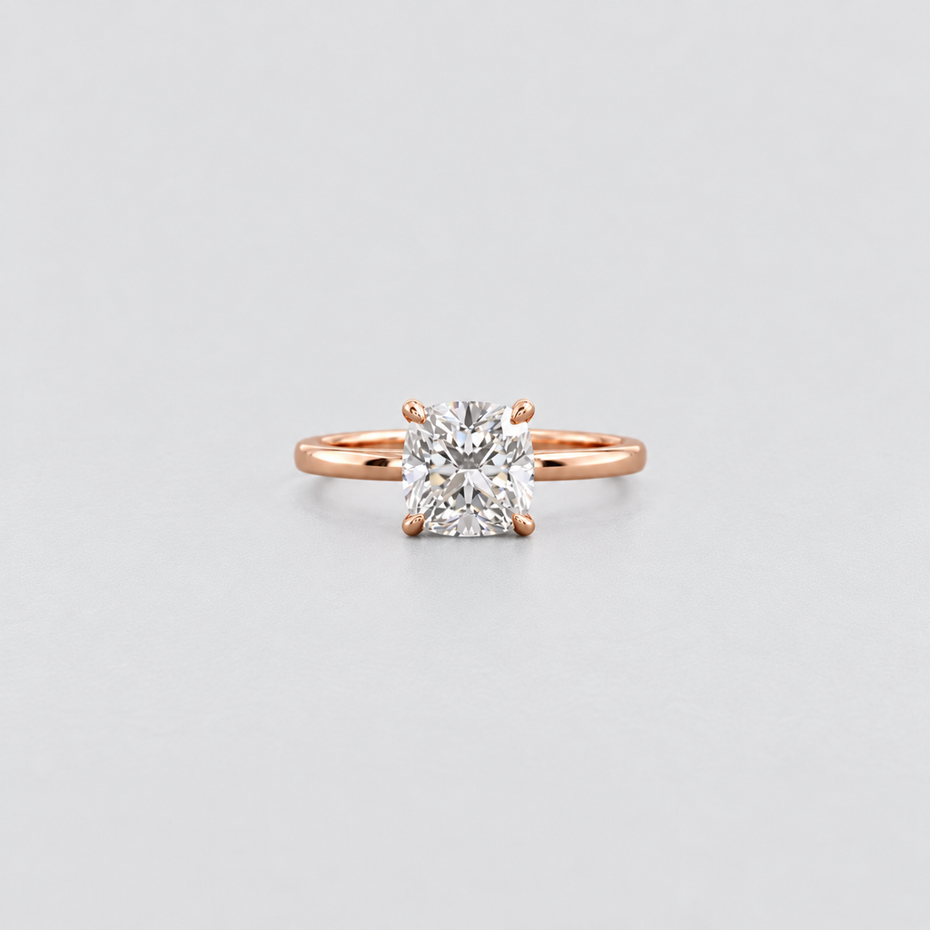 A rose gold solitaire engagement ring with a brilliant round-cut diamond set in a four-prong setting, centered on a light gray background.