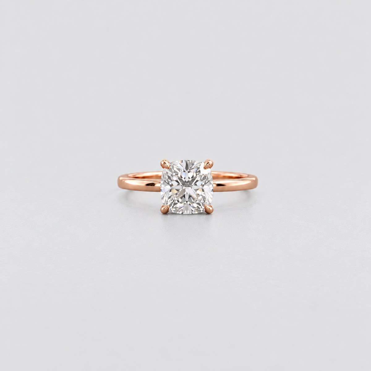 A rose gold solitaire engagement ring with a brilliant round-cut diamond set in a four-prong setting, centered on a light gray background.