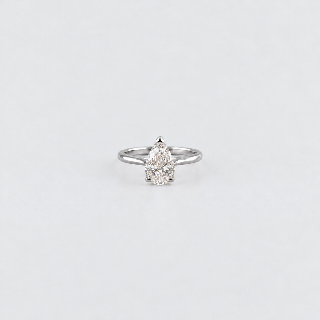 A silver ring featuring a pear-cut diamond cluster setting, centered on a plain light gray background.