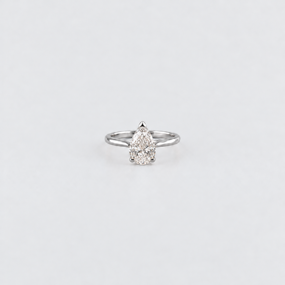 A silver ring featuring a pear-cut diamond cluster setting, centered on a plain light gray background.