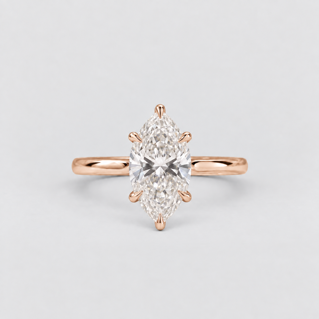 A rose gold ring featuring a marquise-cut diamond center stone in a six-prong setting, shown against a clean, light gray background.