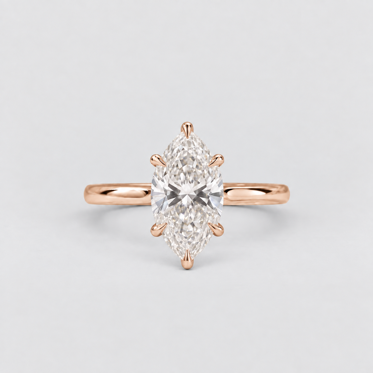 A rose gold ring featuring a marquise-cut diamond center stone in a six-prong setting, shown against a clean, light gray background.