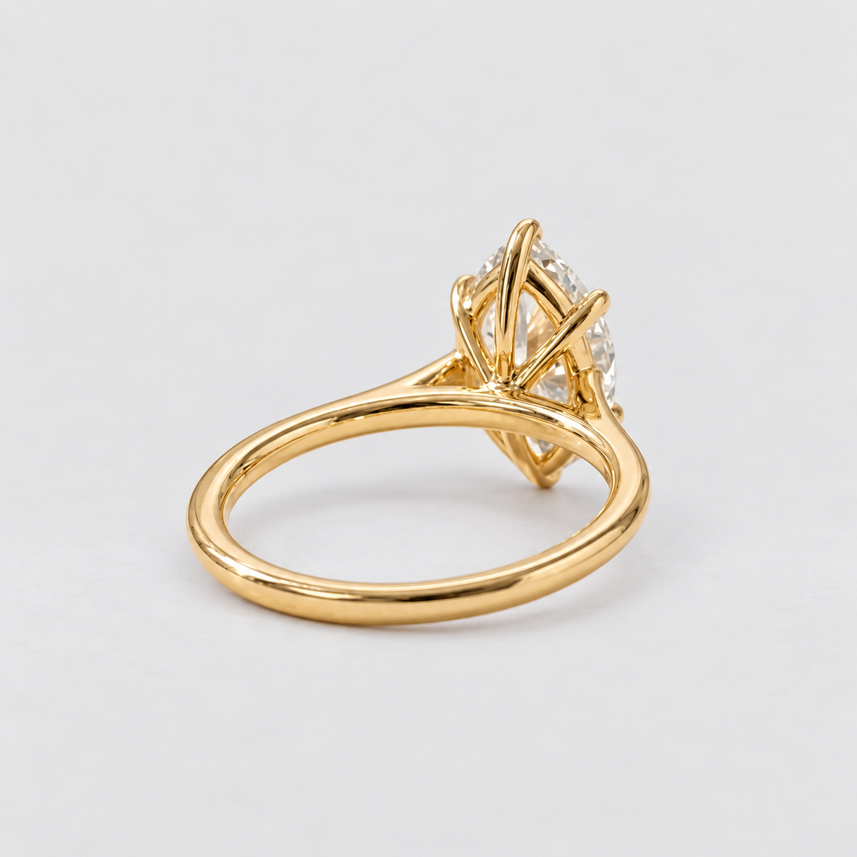 A yellow gold ring with a diamond cluster setting, shown from a side angle on a light gray background.