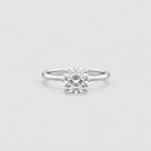 A classic solitaire engagement ring featuring a round brilliant-cut diamond set in a polished white gold or platinum band, centered on a light gray background.