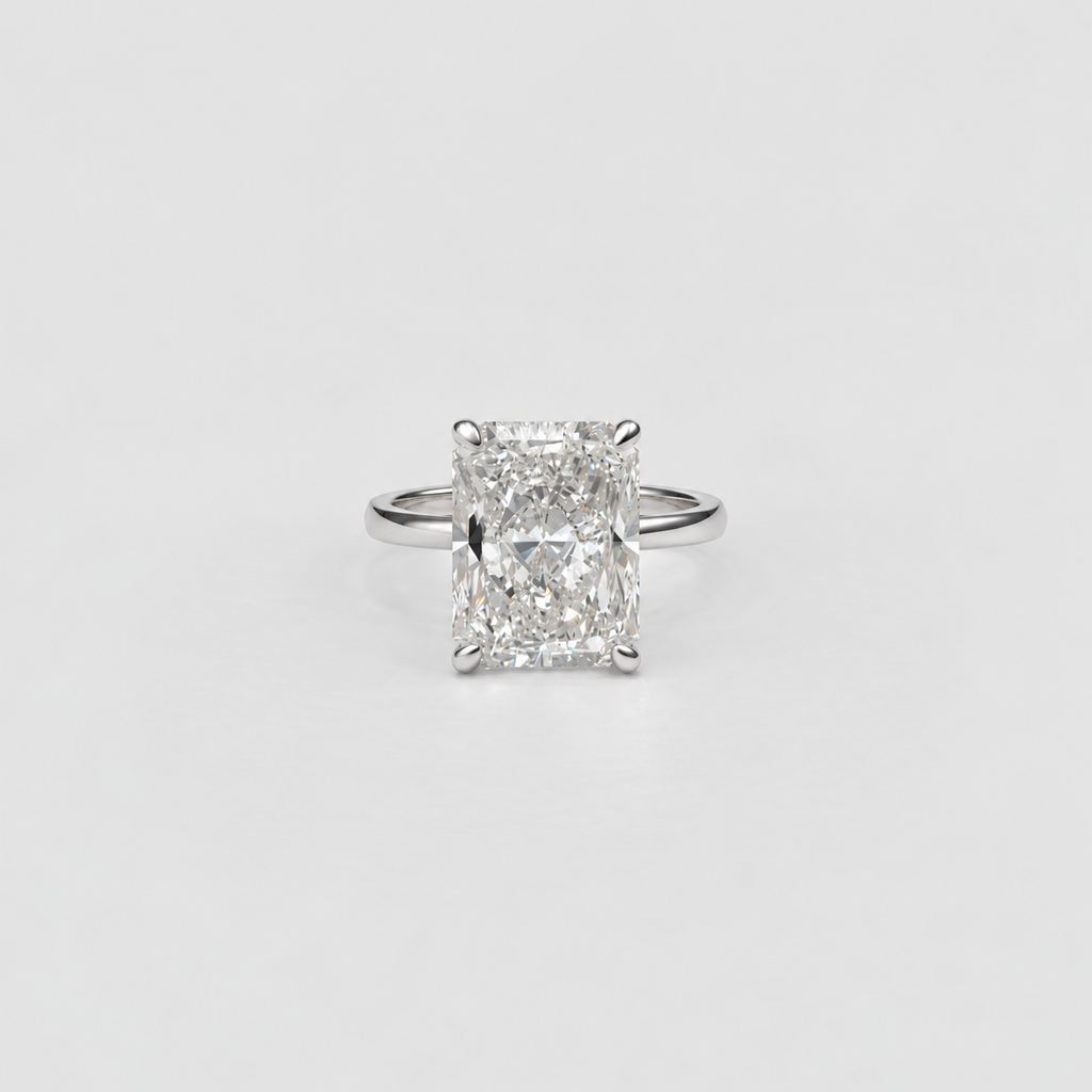 An emerald-cut diamond ring with a silver-toned band, centered on a clean, light gray background.
