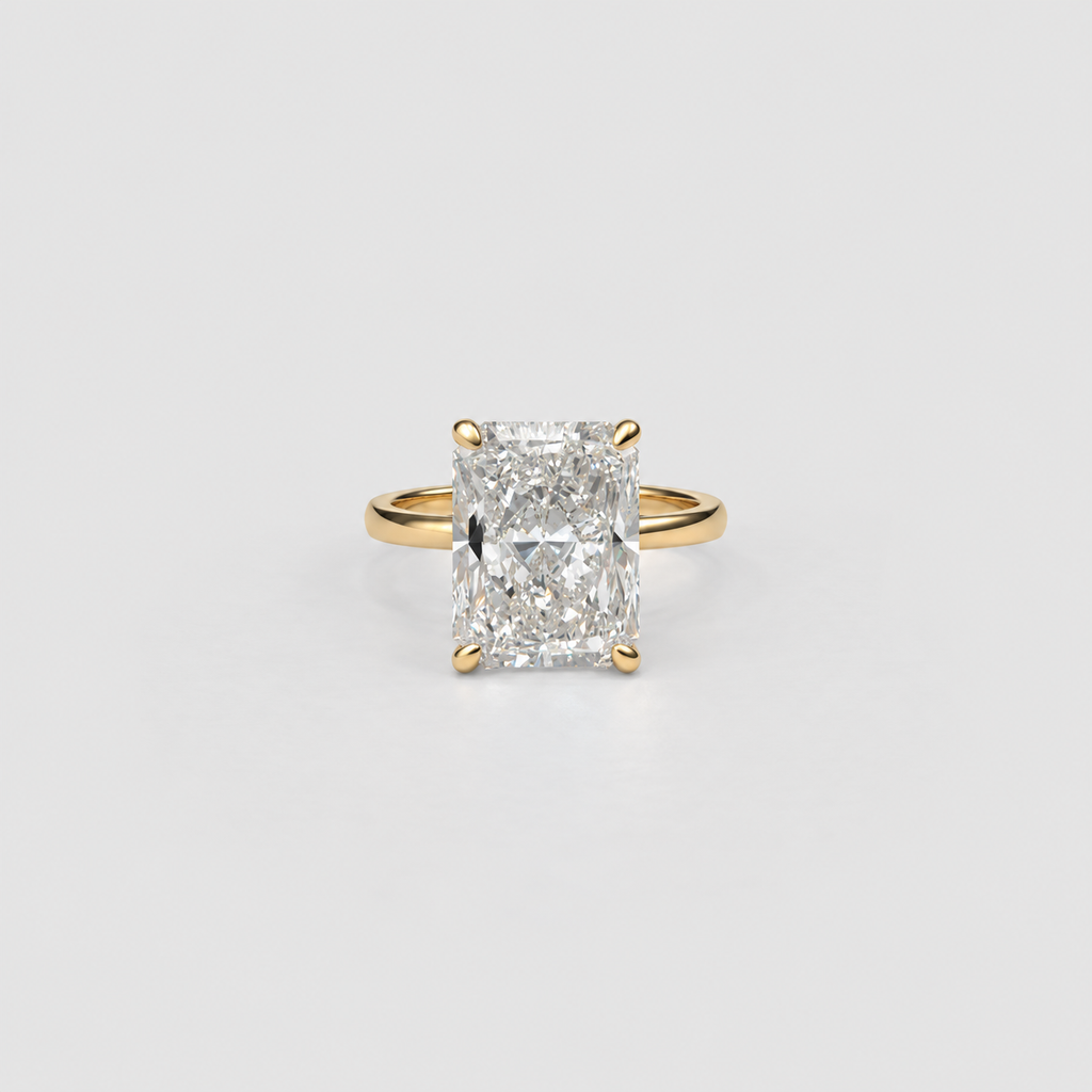 An emerald-cut diamond ring in a yellow gold four-prong setting, centered on a light gray background.
