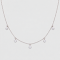 A delicate silver-tone necklace featuring a fine chain with five small, clear crystal flower-like charms spaced along the front, displayed against a light gray background.