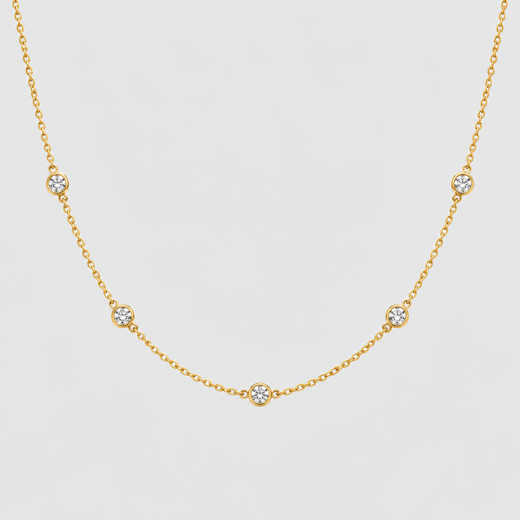 A delicate yellow gold chain necklace featuring five small, evenly spaced round bezel-set clear gemstones on a light gray background.