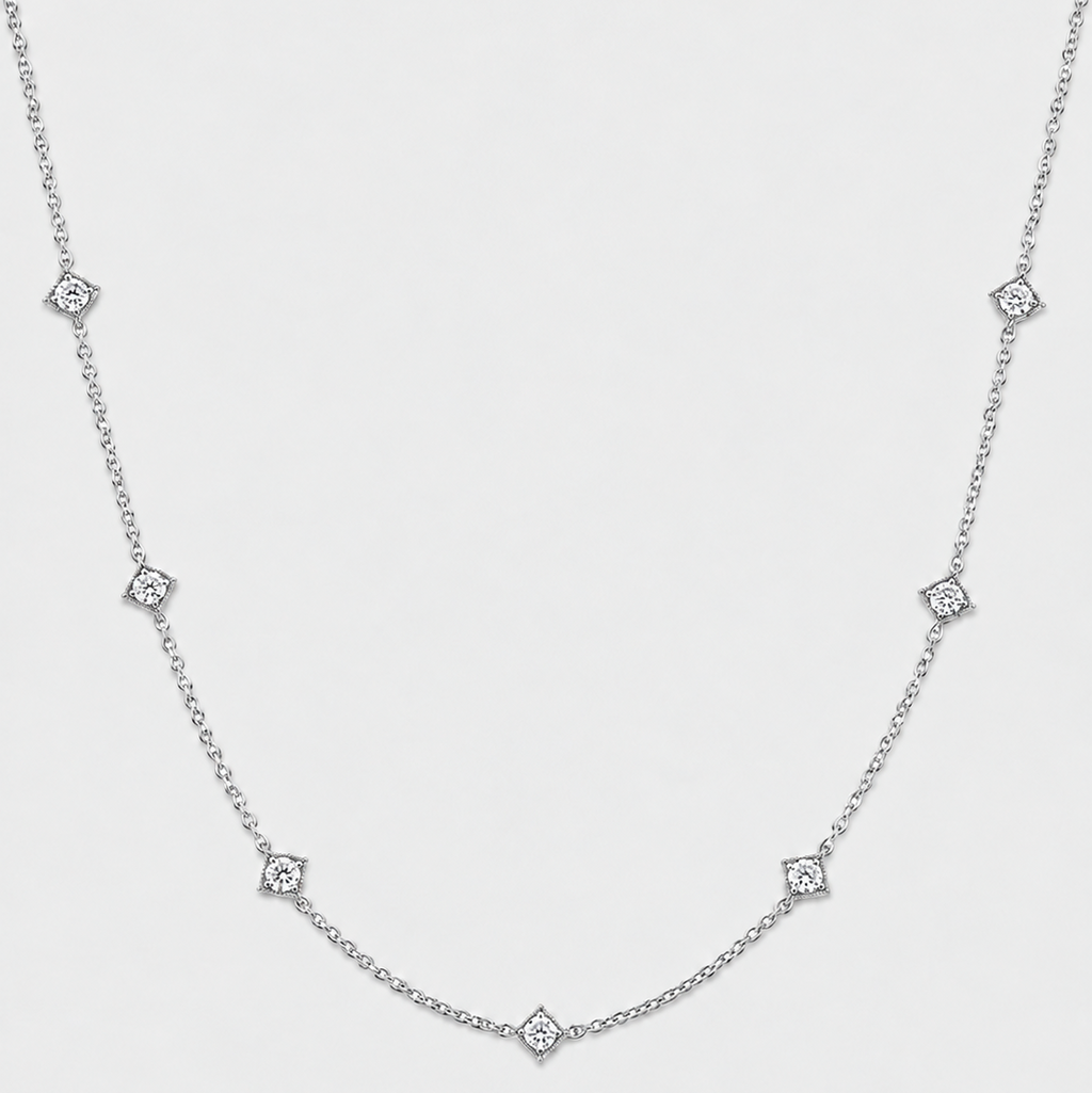 A delicate silver chain necklace featuring small diamond-shaped diamond accents spaced along the chain, photographed against a light gray background.