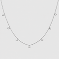 A delicate silver chain necklace featuring seven small, clear round gemstones spaced along the chain, displayed against a solid light gray background.