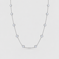 A delicate silver-toned chain necklace featuring seven evenly spaced round bezel-set clear gemstones, displayed against a light gray background.