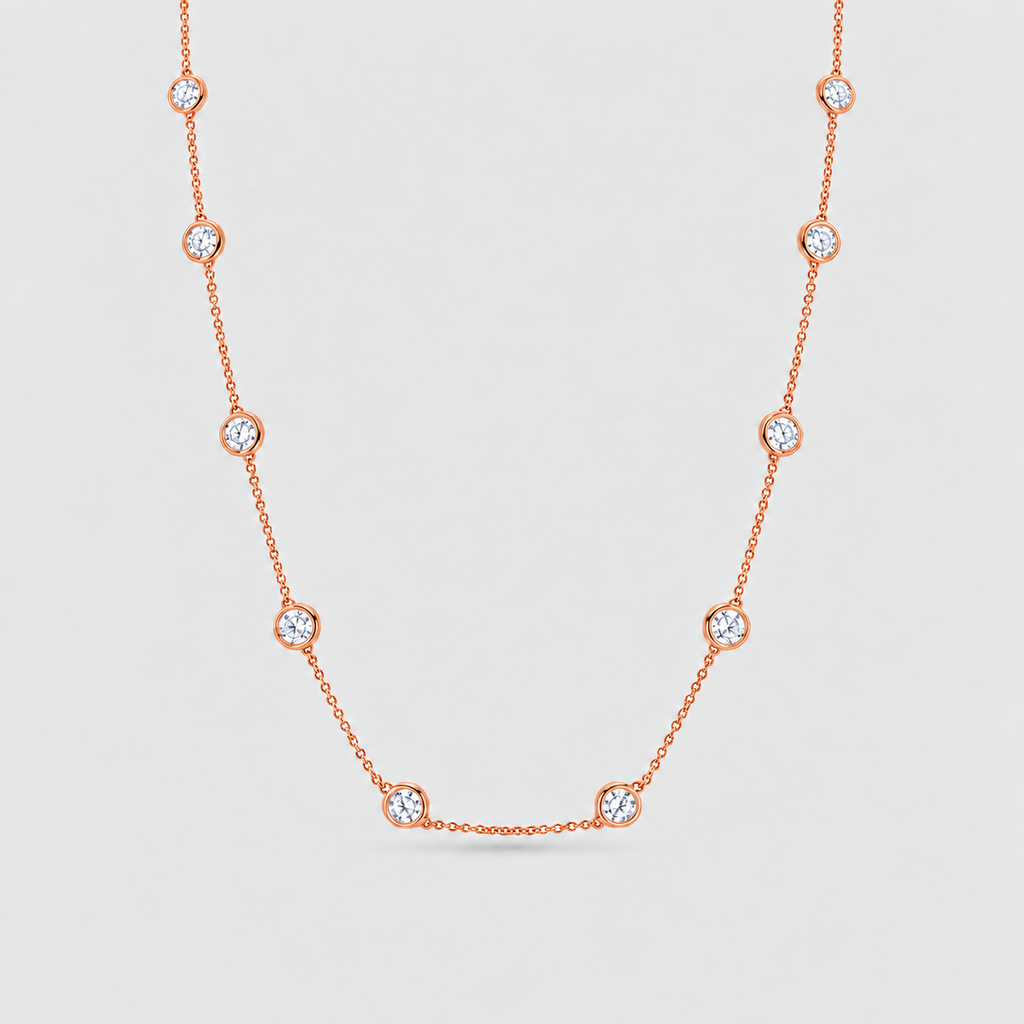 A delicate rose gold chain necklace featuring nine small, bezel-set round clear gemstones spaced evenly along the chain, displayed against a light gray background.