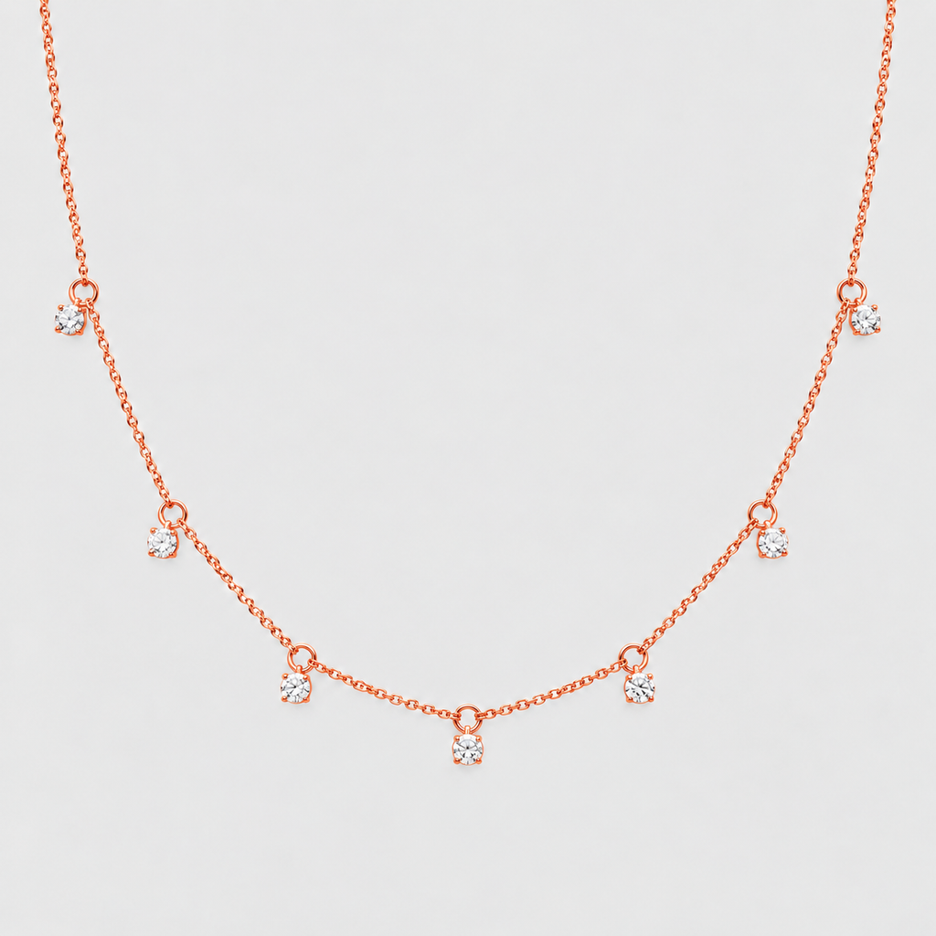 A delicate rose gold necklace featuring a fine chain with seven small, spaced bow-shaped charms, each adorned with a clear round-cut gemstone, set against a solid light gray background.