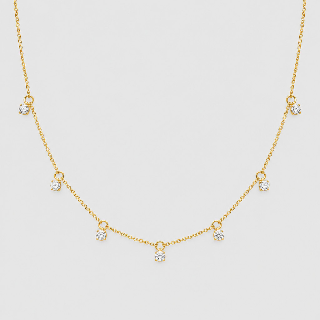 A delicate gold chain necklace featuring seven small, clear heart-shaped crystals spaced along the chain, displayed against a solid light gray background.