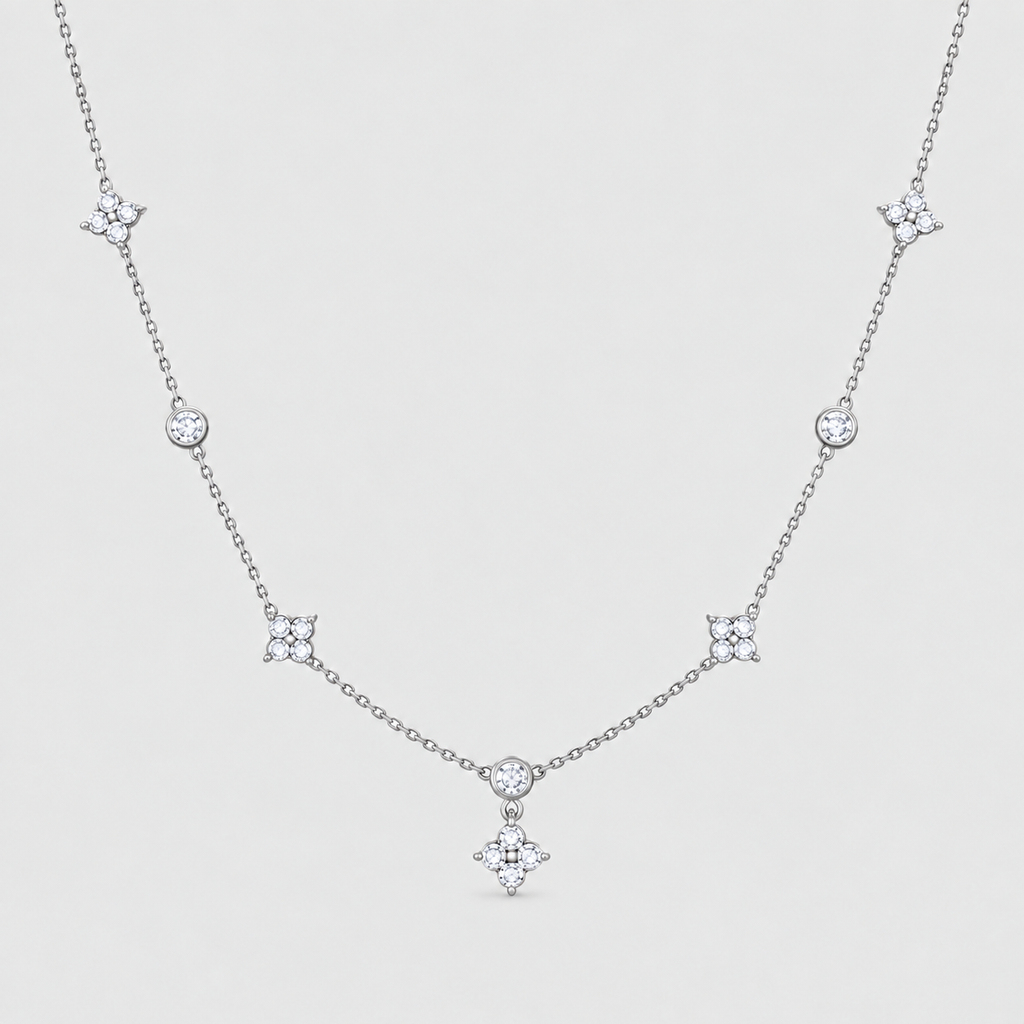 A delicate silver-toned necklace featuring a central diamond-shaped pendant and five matching starburst motifs spaced along the chain, displayed on a light gray background.