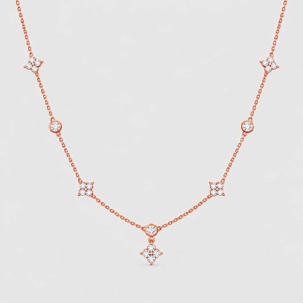 A delicate rose gold chain necklace featuring multiple small diamond-like star and oval motifs spaced along the chain, displayed against a light gray background.