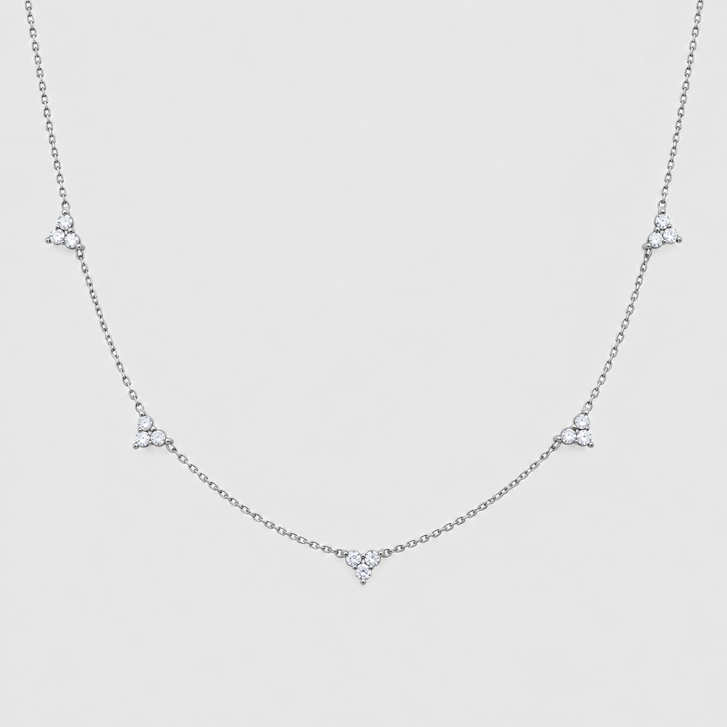 A delicate silver chain necklace featuring five small, clear triangular crystal clusters spaced evenly along the chain, displayed against a light gray background.