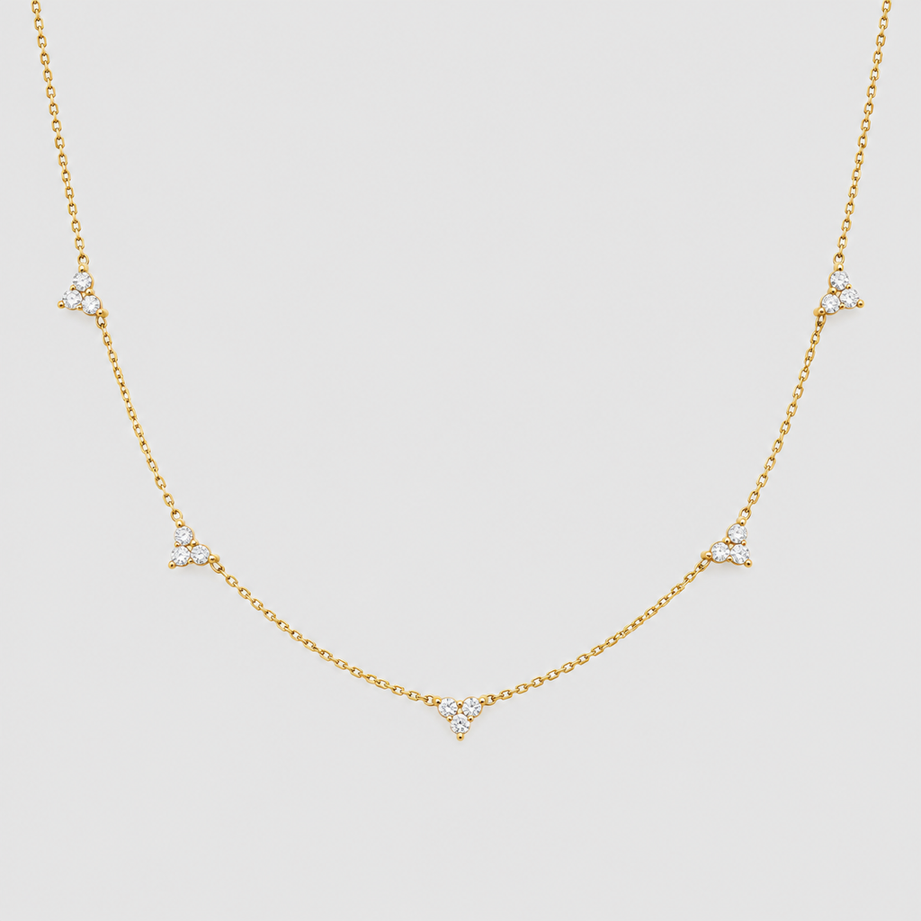 A delicate gold chain necklace featuring five small triangular diamond clusters spaced along the chain, displayed against a solid light gray background.