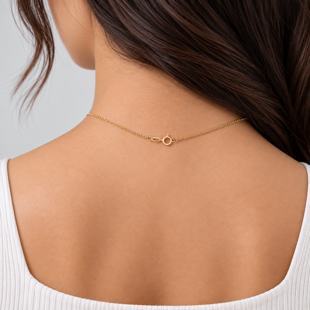A delicate gold chain necklace with a small infinity symbol charm, shown worn on the back of a woman's neck over a white ribbed top.