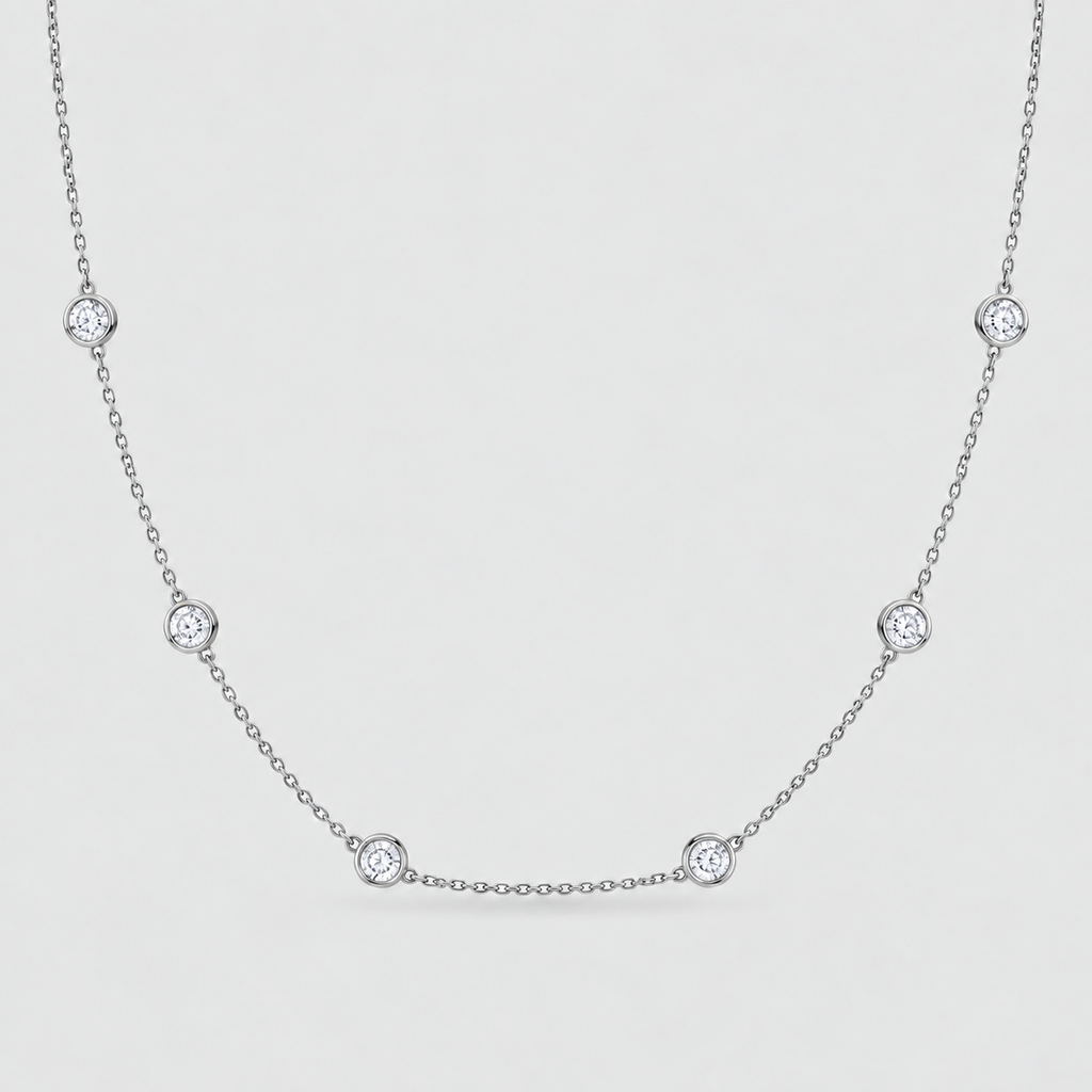 A delicate silver chain necklace featuring five evenly spaced round bezel-set clear gemstones on a light gray background.