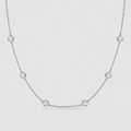 A delicate silver chain necklace featuring five evenly spaced round bezel-set clear gemstones on a light gray background.