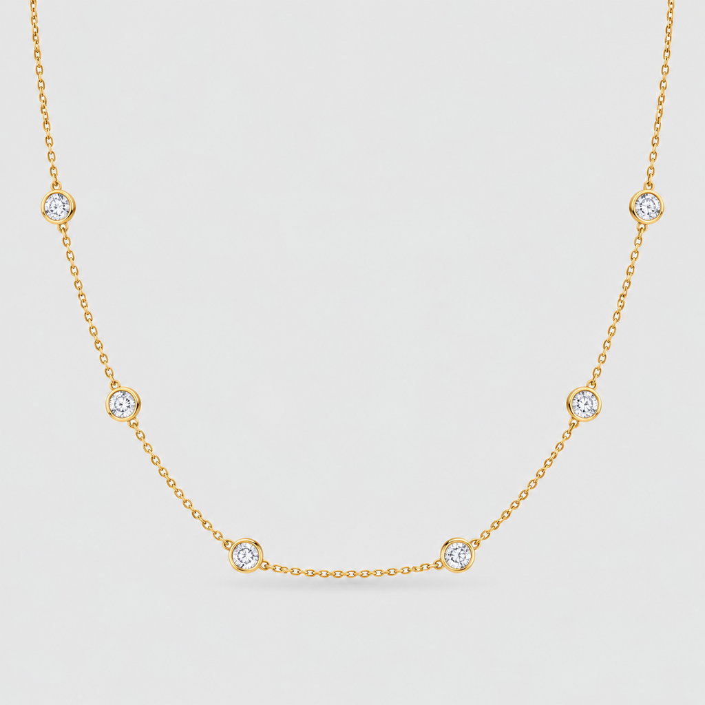 A delicate yellow gold chain necklace featuring five evenly spaced round bezel-set clear gemstones on a light gray background.