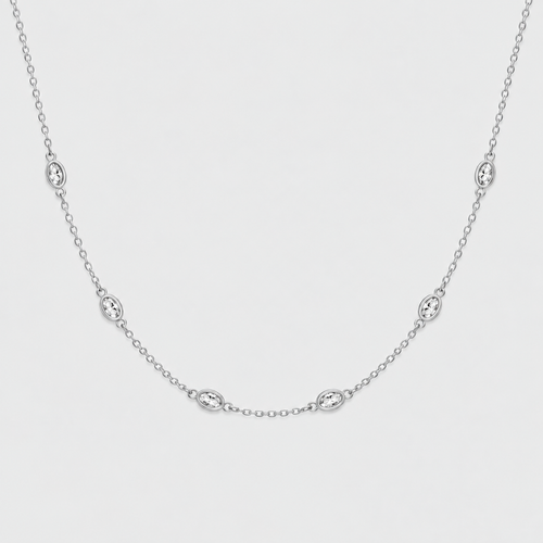 A delicate silver chain necklace featuring five small oval bezel-set clear stones, displayed against a clean, light gray background.