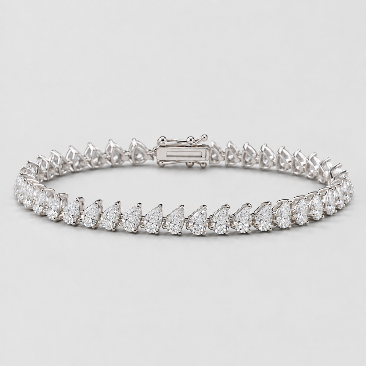 A diamond tennis bracelet featuring pear-cut and round diamonds set in a silver-colored metal, shown on a light gray background.