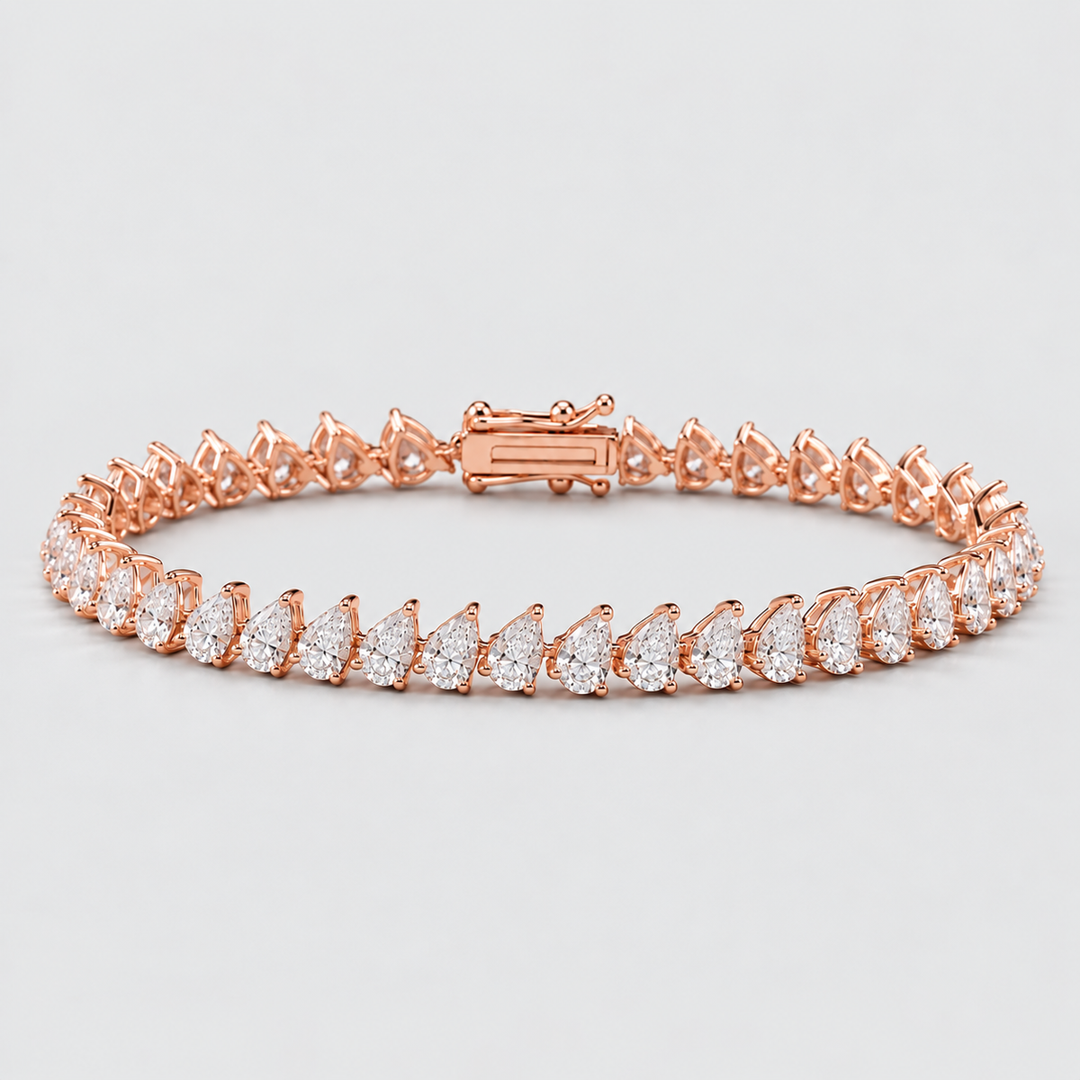 A rose gold tennis bracelet featuring a row of pear-cut clear gemstones in a continuous link design, displayed on a light gray background.