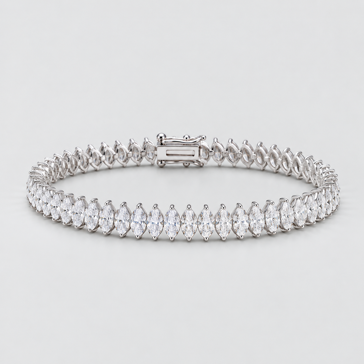 A tennis bracelet featuring marquise-cut clear stones in a silver-toned setting, arranged in a continuous row with a rectangular clasp, shown on a light gray background.