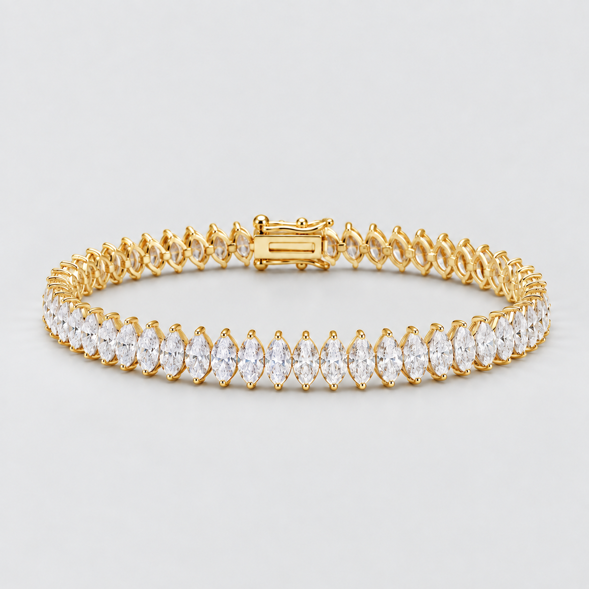 A yellow gold tennis bracelet featuring a row of marquise-cut clear gemstones, displayed on a light gray background.