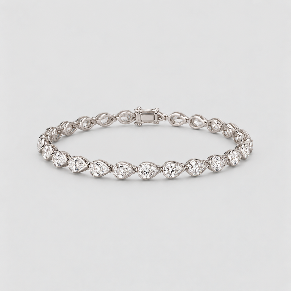 A silver tennis bracelet featuring pear-cut clear gemstones in a continuous row, displayed on a clean light gray background.