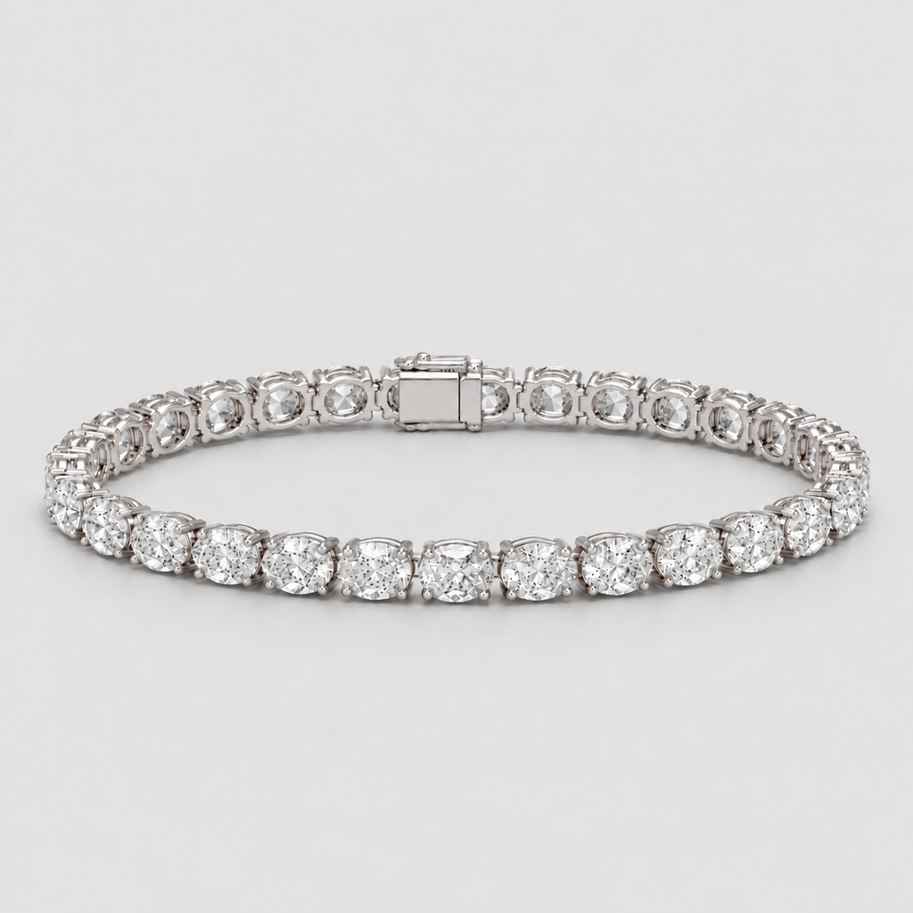 A diamond tennis bracelet in a silver-toned setting, featuring round brilliant-cut diamonds and a rectangular clasp, photographed on a light gray background.