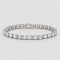 A diamond tennis bracelet in a silver-toned setting, featuring round brilliant-cut diamonds and a rectangular clasp, photographed on a light gray background.
