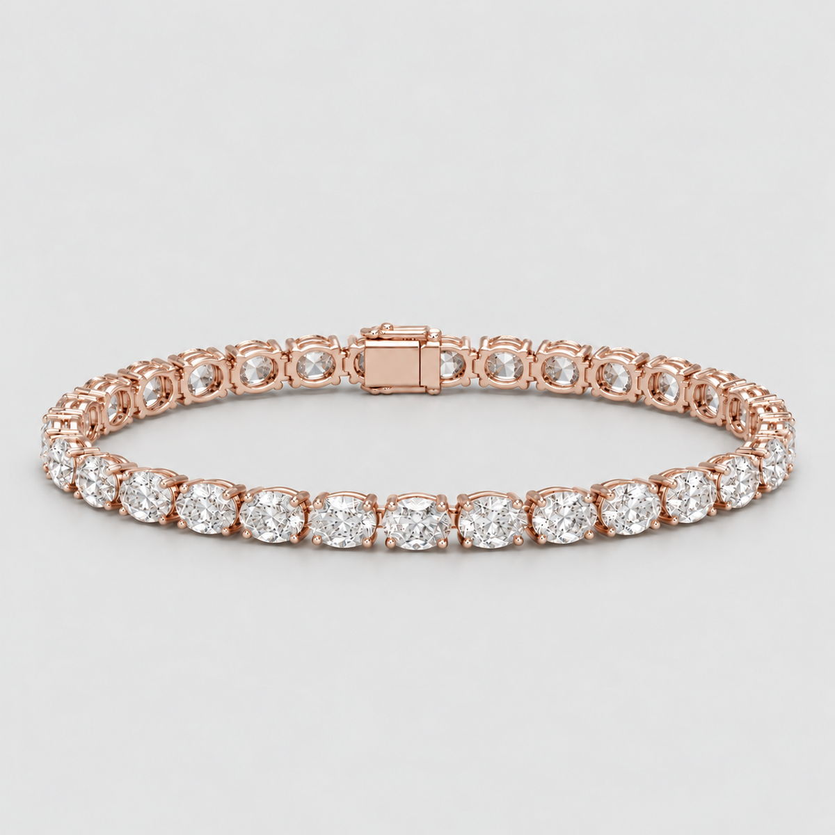 A rose gold tennis bracelet with round-cut clear gemstones, displayed on a light gray background.