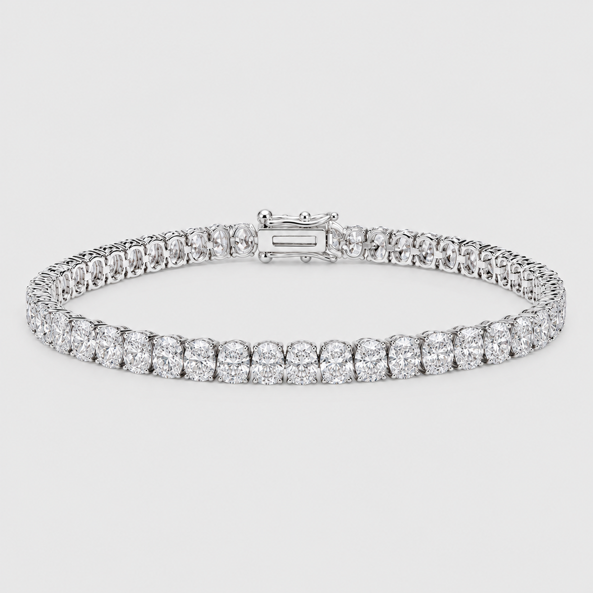 A diamond tennis bracelet with a row of round-cut diamonds and a baguette clasp, shown on a light gray background.