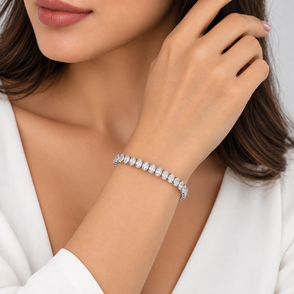 A close-up lifestyle shot of a woman wearing a sparkling silver tennis bracelet on her wrist, with her hand resting near her face.