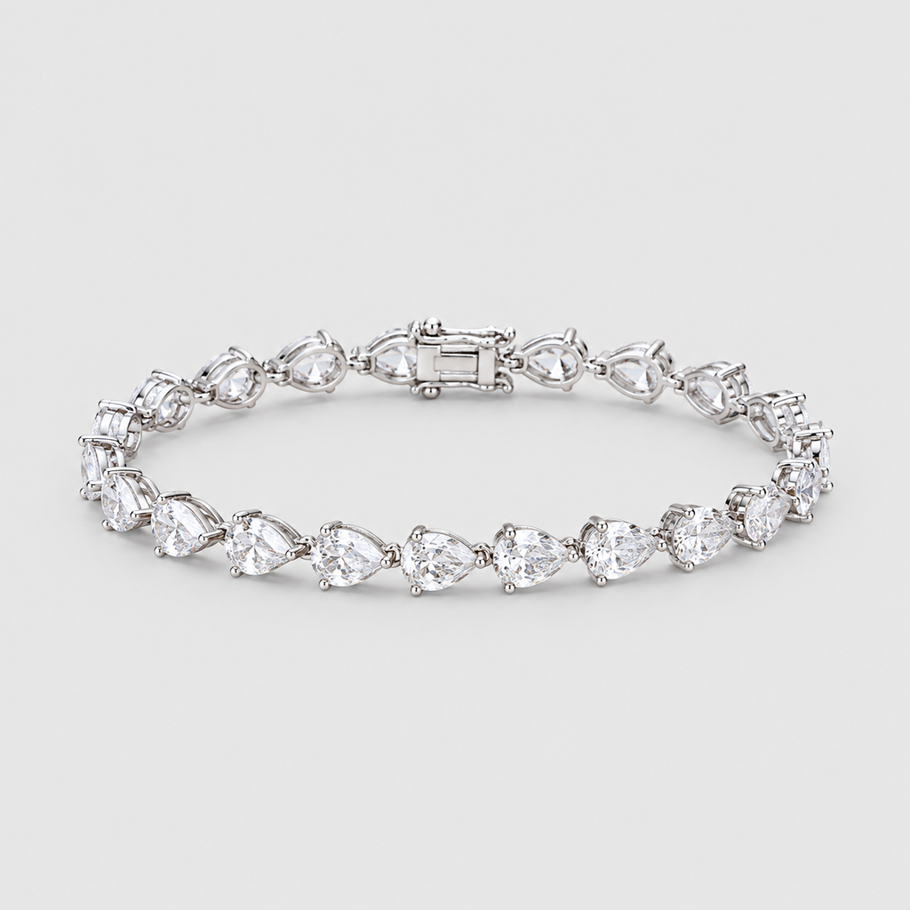 A silver tennis bracelet featuring a row of pear-cut clear gemstones in a prong setting, displayed on a light gray background.