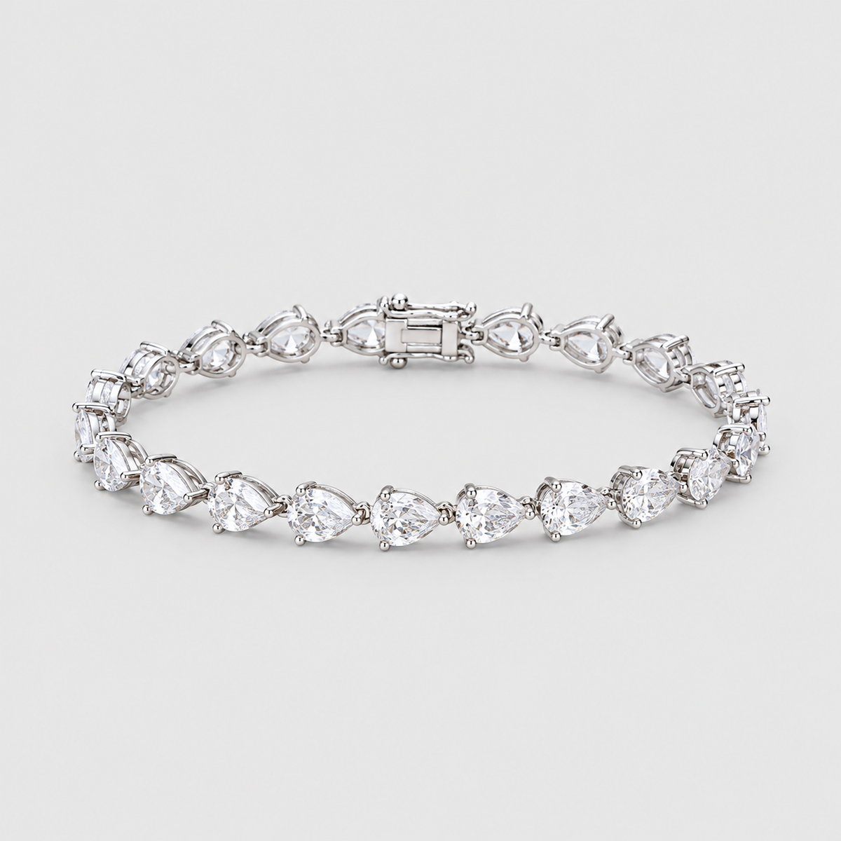 A silver tennis bracelet featuring a row of pear-cut clear gemstones in a prong setting, displayed on a light gray background.
