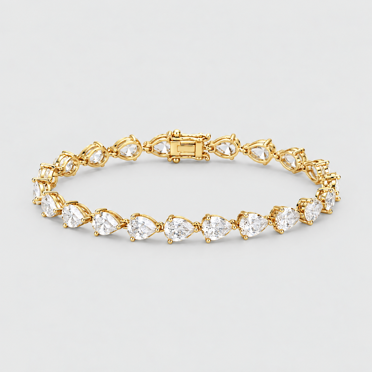 A yellow gold tennis bracelet featuring a continuous row of pear-cut clear gemstones in a prong setting, displayed on a light gray background.